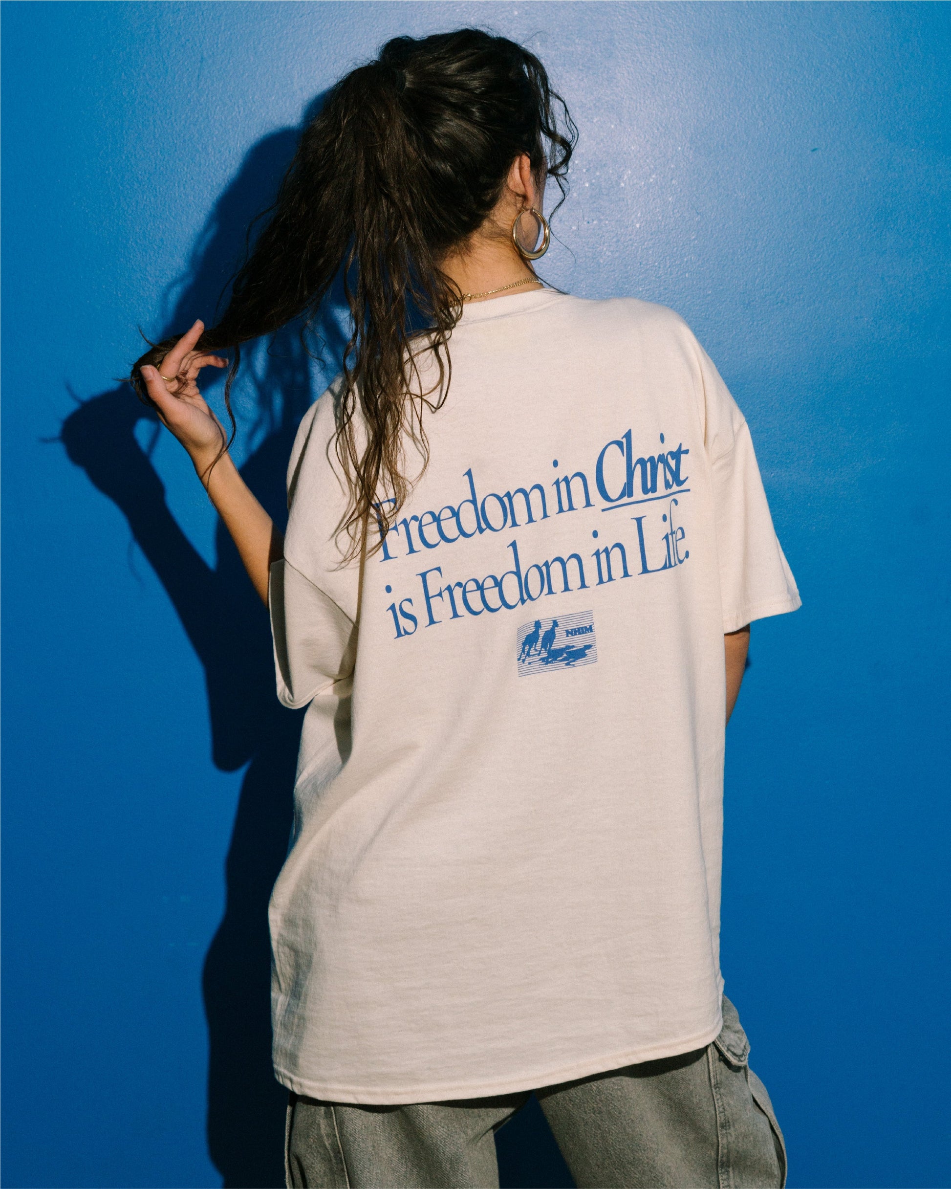 FREEDOM IN CHRIST TEE (cream/blue) on a model by NHIM Apparel Christian clothing brand