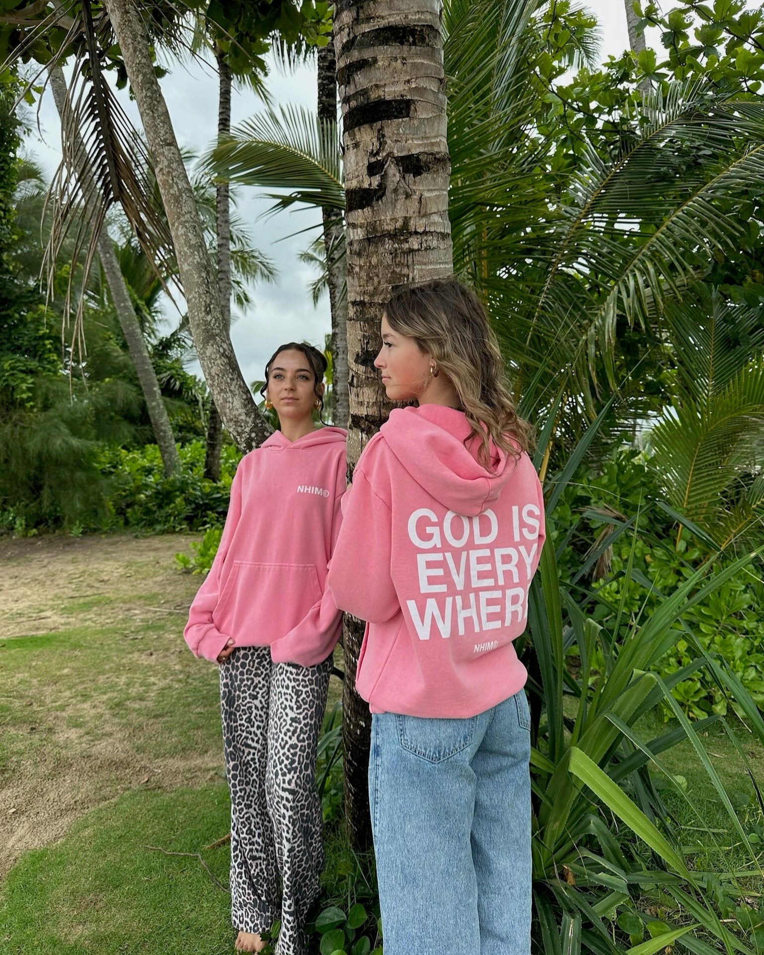 two girls standing on a beach in kauai wearing God is Everywhere hoodies in vintage pink by NHIM apparel christian clothing brand