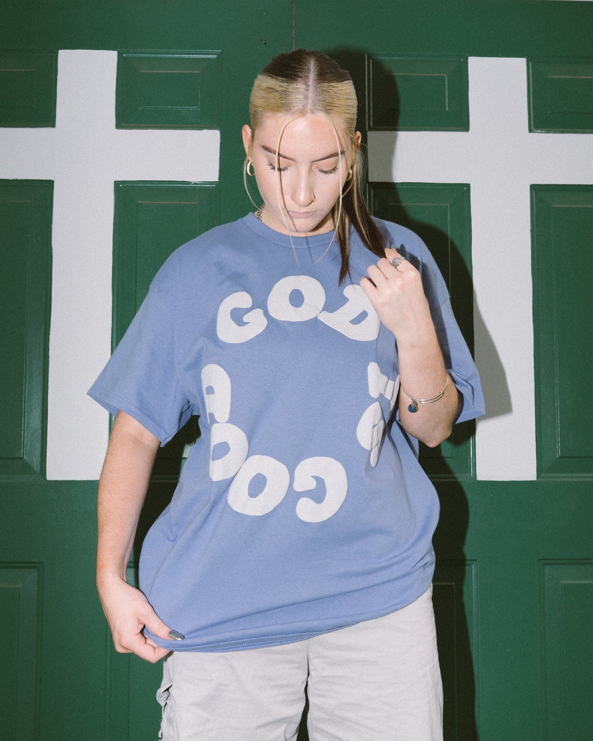 woman wearing God is Good christian t shirt in front of green church doors with white crosses on them in Atlanta, Georgia