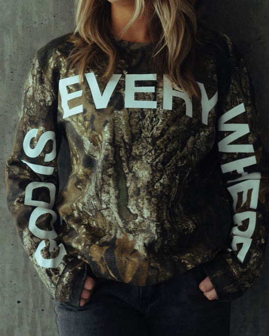 female model standing in god is everywhere camo long sleeve shirt by nhim apparel christian clothing brand