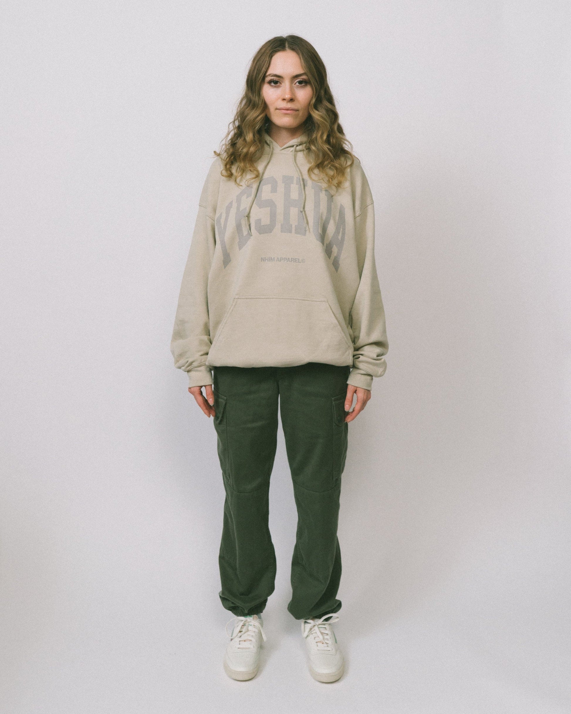 Yeshua hoodie YESHUA logo sand color hooded sweatshirt made by NHIM APPAREL christian clothing brand, model standing wearing yeshua hoodie