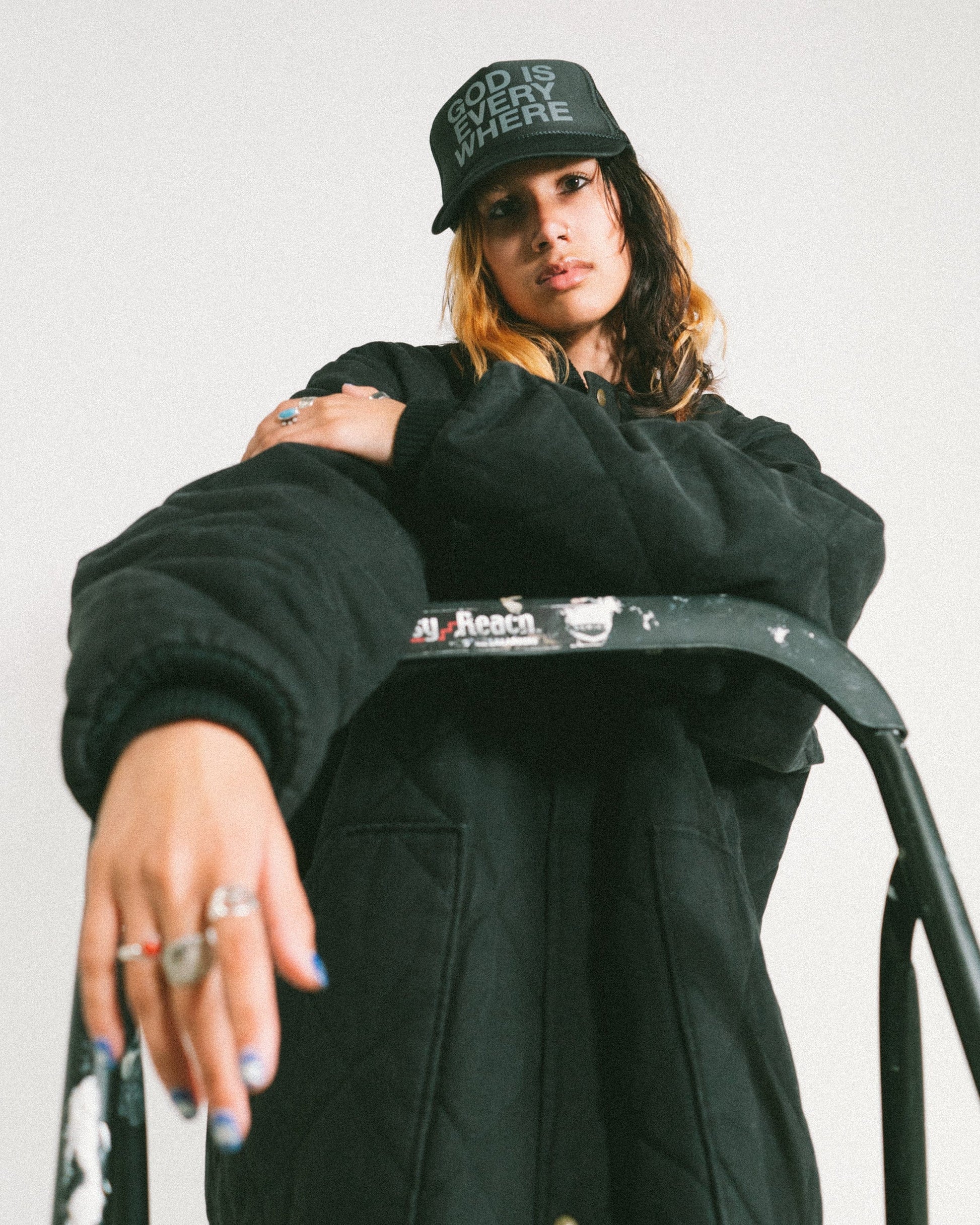 God is Everywhere Black Trucker Hat with grey writing, NHIM APPAREL. model standing with black christian hat and black jacket