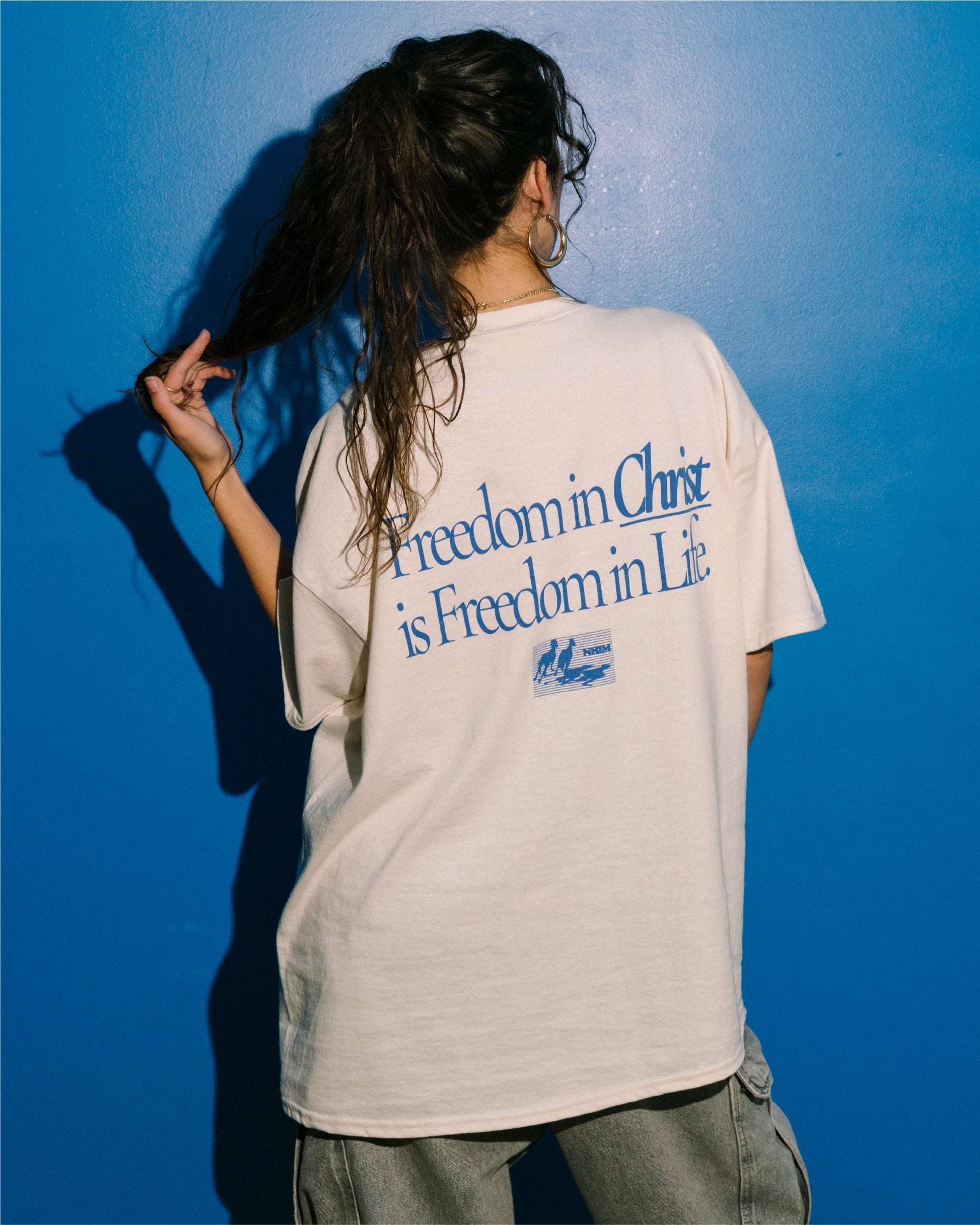 FREEDOM IN CHRIST TEE (cream/blue) on a model by NHIM Apparel Christian clothing brand