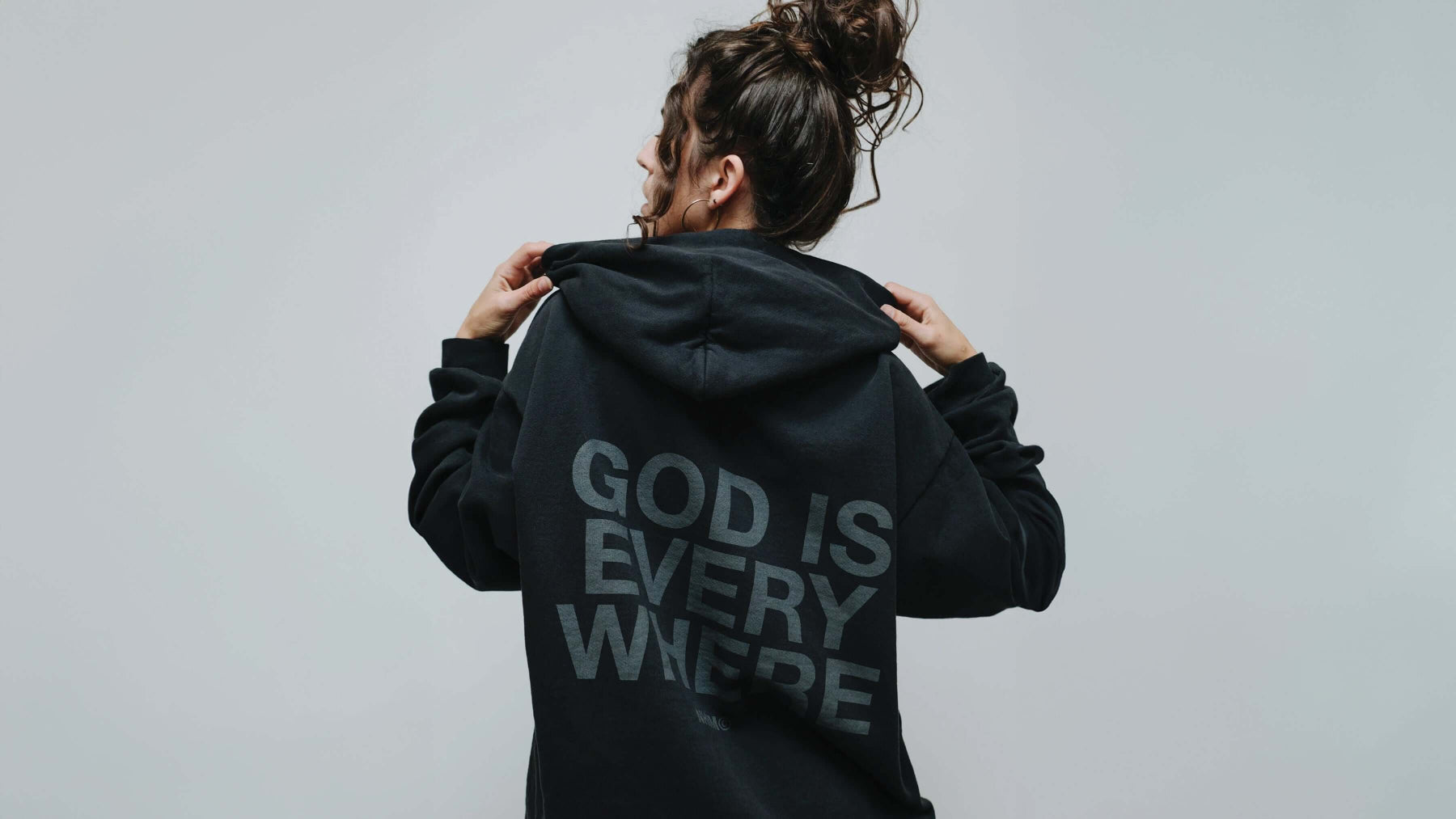 God is Everywhere blackout hoodie homepage banner image with Elise by NHIM Apparel