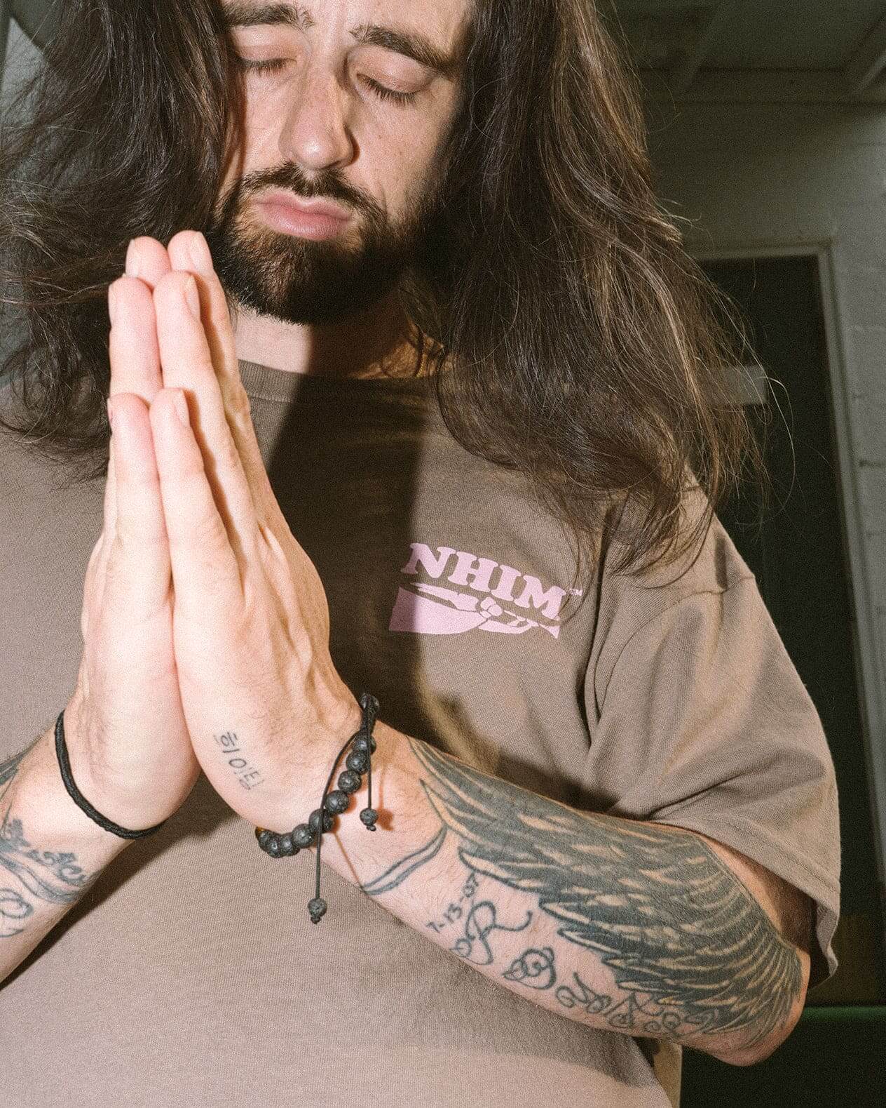 model wearing Christian t shirt by nhim apparel in front of church folding hands to pray