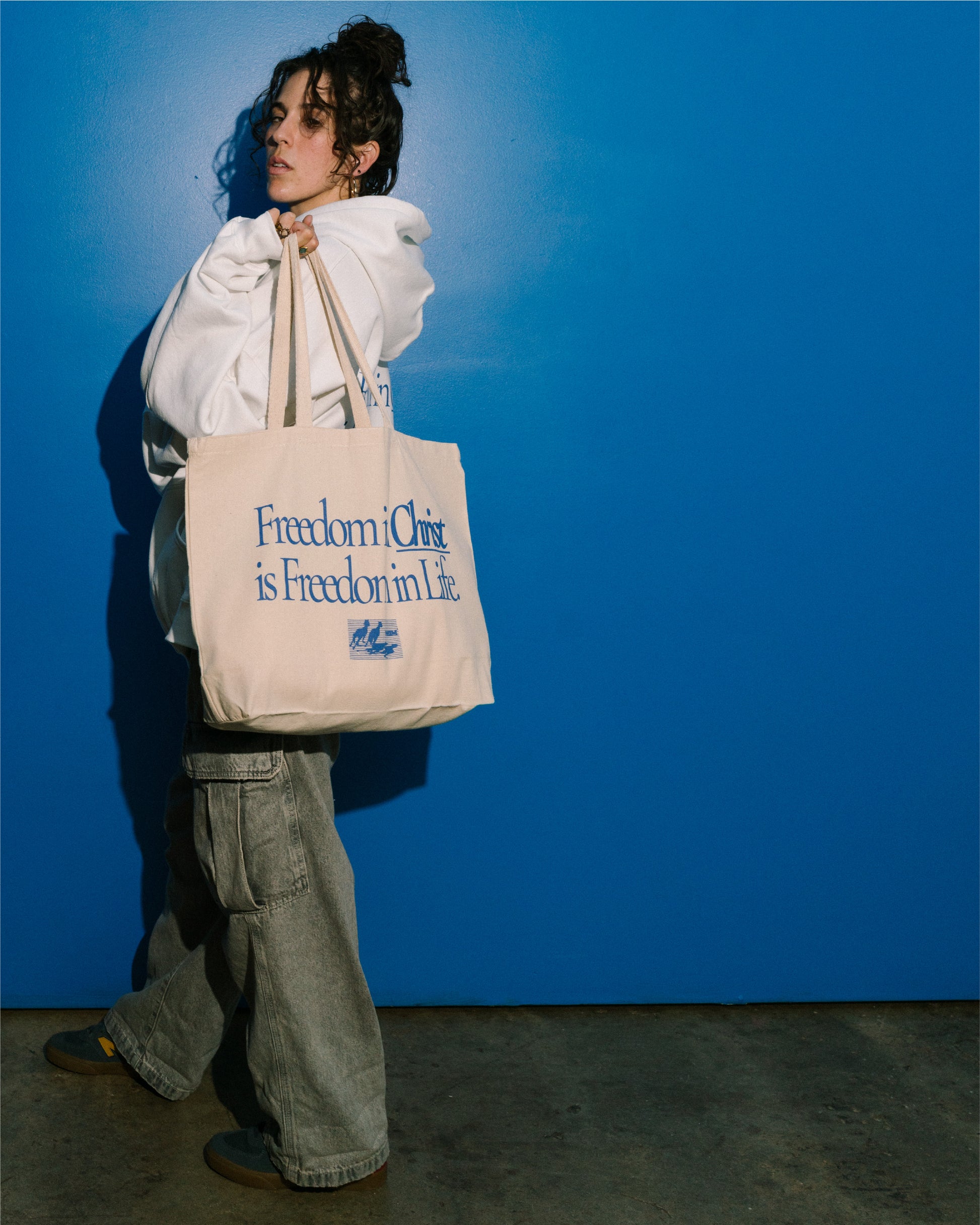 FREEDOM IN CHRIST SHOULDER TOTE (NATURAL) on a model by NHIM Apparel Christian clothing brand