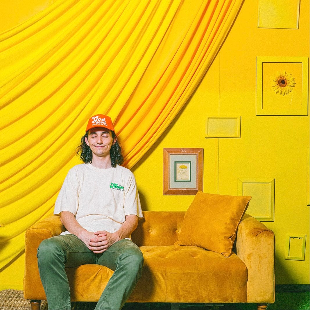 Christian hat. Christian t shirt. God is good all the time. Orange trucker hat. Green t shirt. NHiM Apparel. Happy chilling on the couch. yellow room.